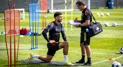 足球运动员伤病恢复训练，队医陪同在训练场